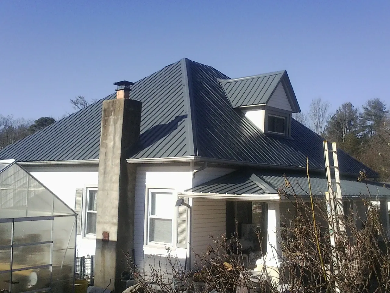 Dark blue standing seam metal roof on a white farmhouse with dormer — Slate & Tile Roof Repair by Roofing Brothers in Lairdsville