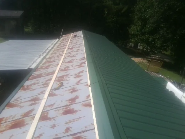 Old rusted panels beside newly installed green metal roofing — Wind Damage Roof Repair by Roofing Brothers in Lairdsville