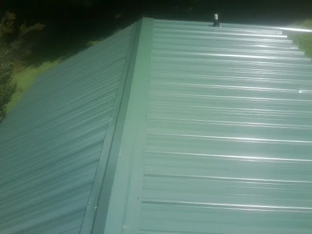 New green metal panels meeting at the ridge of a roof — Flat Roof Repair work by our crew in Lairdsville