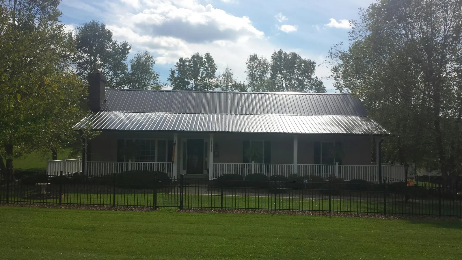 Gray metal roof on a brick ranch with a full width front porch — Gutter Guard Installation work by our crew in Lairdsville
