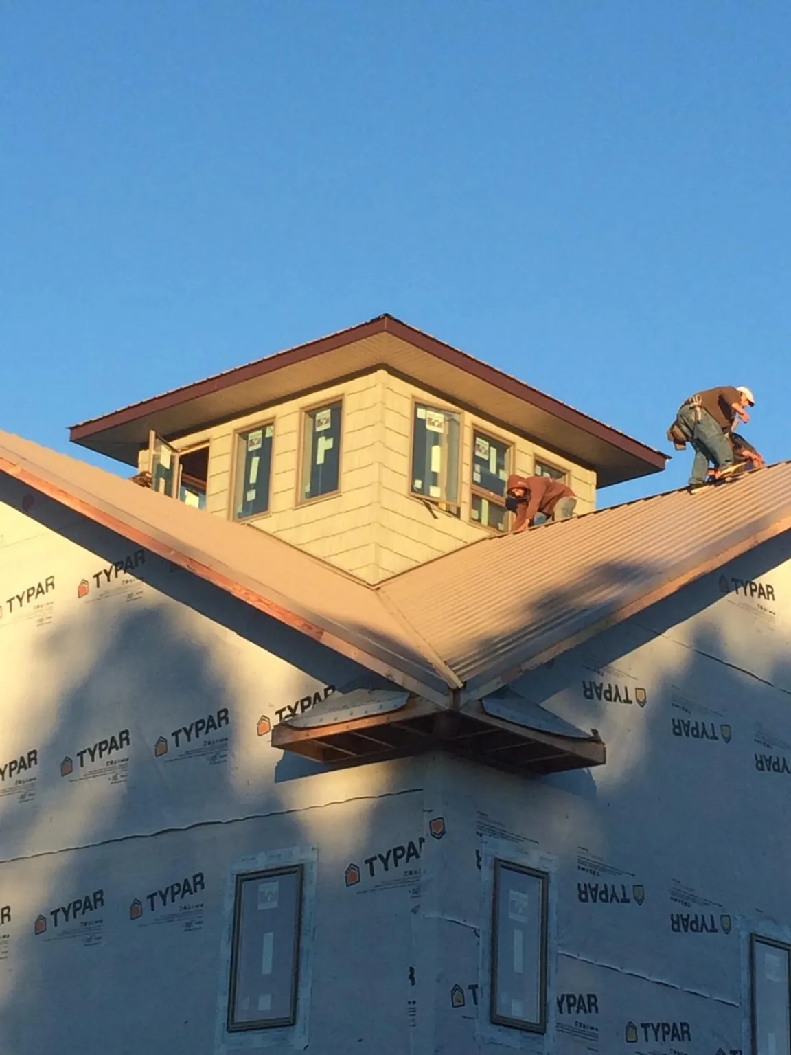 Roofers working around a rooftop cupola on a new metal roof at sunset — Roof Waterproofing in Lairdsville by Roofing Brothers